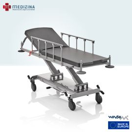 Abb. zeigt den Novak M Stretcher »SL« mit Schiebegriffen und Wandabweisern am Kopf- und Fußende sowie Seitengittern. Ausgestattet mit hydraulischer Höhenverstellung, verstelltem Kopfteil, 80 mm Matratze und antistatischen Rollen (Ø 150 mm).