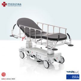 Abb. zeigt den Novak M Stretcher »X2« 4-tlg. mit Schiebegriffen und Wandabweisern am Kopf- und Fußende sowie Seitengittern. Ausgestattet mit hydraulischer Höhenverstellung, verstelltem Kopf-, Bein- und Fußteil und 60 mm rutschfester Matratze.